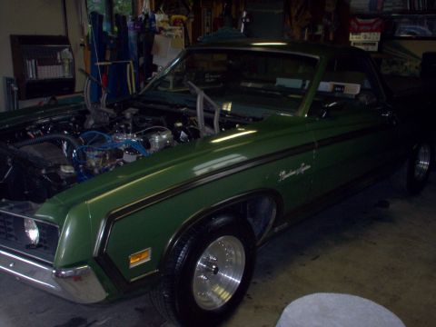 1970 Ford Ranchero - A green 1970 Ford Ranchero is parked in a garage with its hood open, revealing the engine.