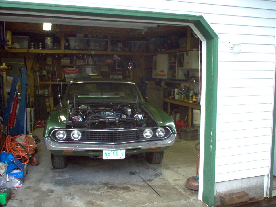 Green vintage Ford front end with hood off in a cluttered garage, Florida plate NX 59 V.