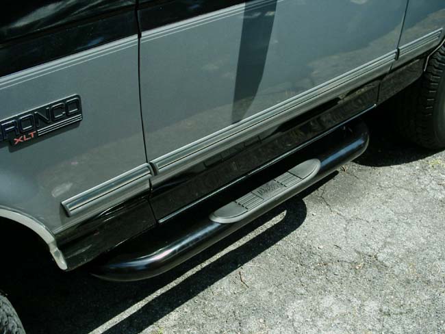 Close-up of silver Bronco XLT body emblem with black nerf step bar below the door