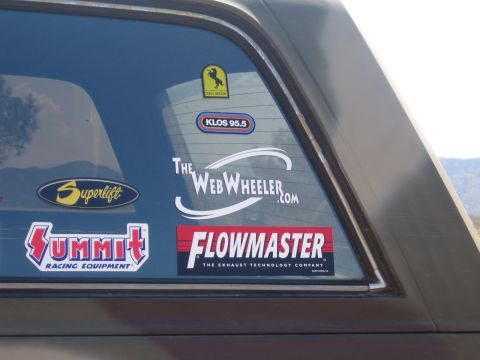 1990 Ford Bronco - Close-up of a truck's rear window plastered with decals: Flowmaster, Summit Racing, Superlift, KLOS 95.5 and TheWebWheeler.com.