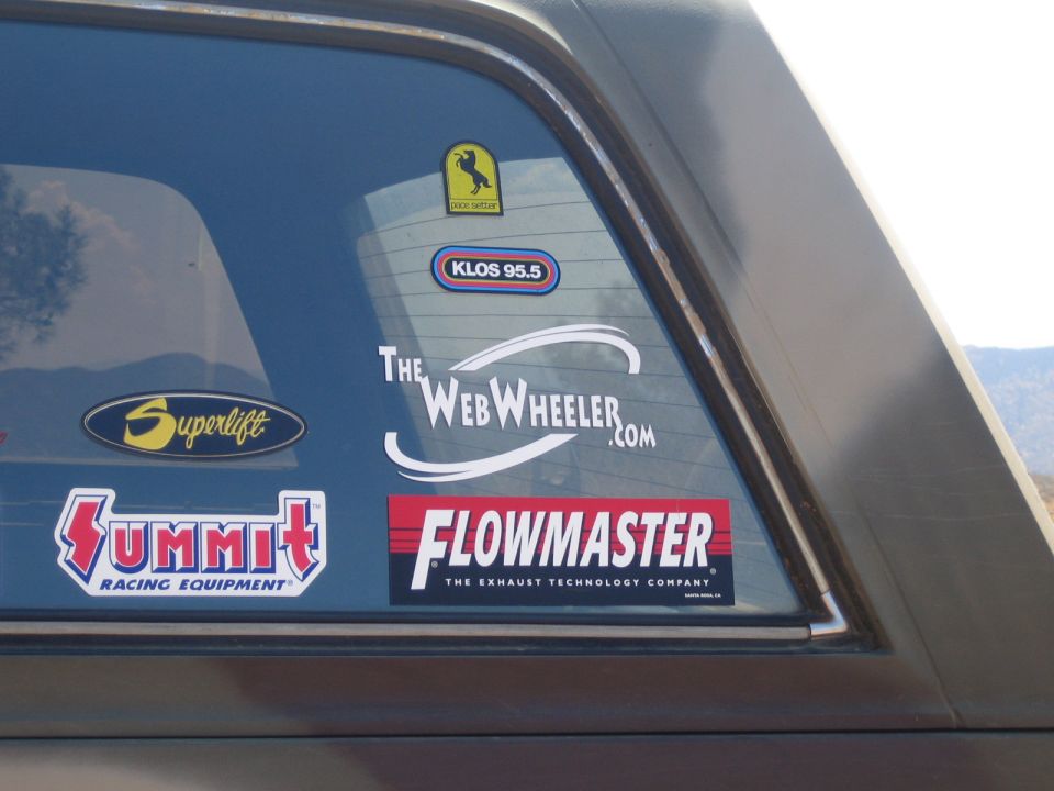 Truck rear window covered in racing decals including Flowmaster, Summit and Superlift