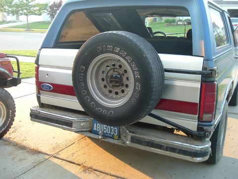 1982 Ford Bronco - This 1982 Ford Bronco displays its rear end, complete with a mounted spare tire and a distinctive red stripe along its side.