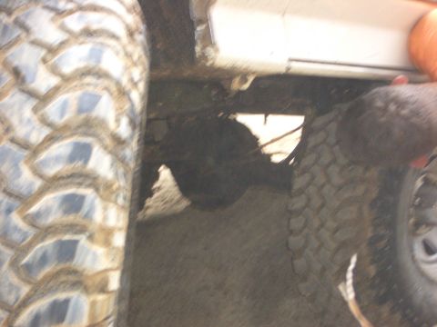 1990 Ford Bronco - Close-up of a vehicle's undercarriage and tires, focusing on the drivetrain components.