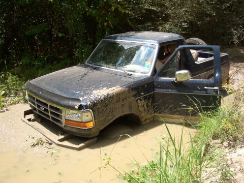 1990 Ford Bronco - This Ford Bronco is stuck deep in a mud pit with its driver's side door open.