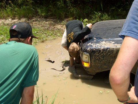 1990 Ford Bronco - People working to free a mud-stuck 1990 Ford Bronco.