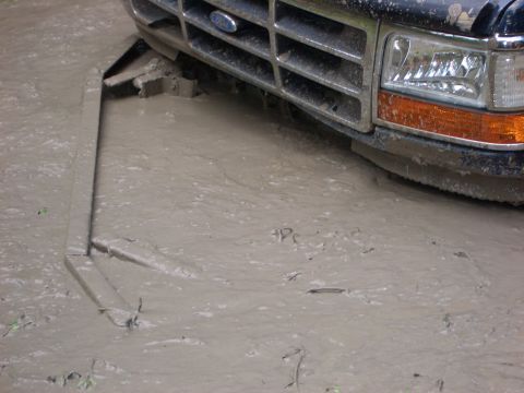 1990 Ford Bronco - This Ford truck is stuck in mud, with its front grille and headlight partially submerged.