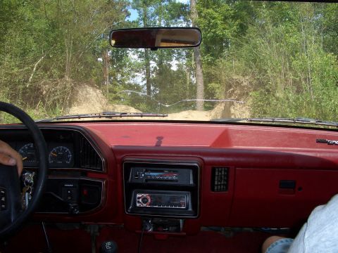 1990 Ford Bronco - Interior view of a 1990 Ford Bronco, showing the dashboard and steering wheel as the vehicle navigates an off-road trail.