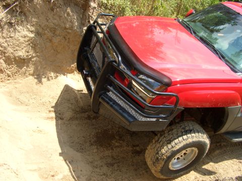 1990 Ford Bronco - SUV with bull bar navigating a steep dirt embankment.