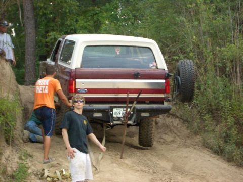1990 Ford Bronco - 1990 Ford Bronco navigating a steep dirt path with assistance from bystanders.