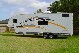 1993 Ford Bronco - A white travel trailer with gold graphics is parked on a grassy area with trees in the background.