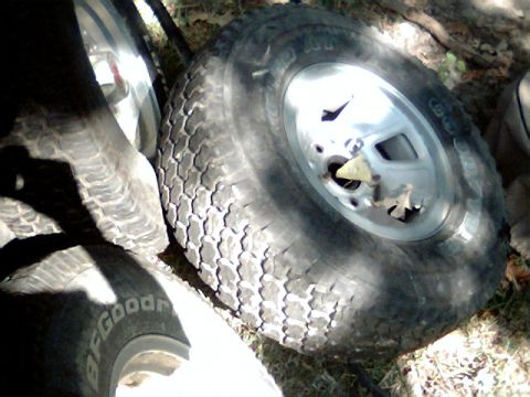 1992 Ford Bronco - A collection of spare tires, including one with a BFGoodrich brand tire, are piled on the ground.
