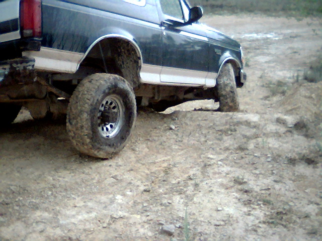 Dark green and white 1992 Ford Bronco on a dirt track, front right wheel turned