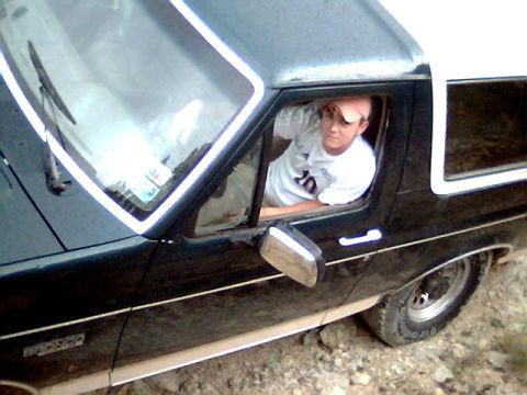 1992 Ford Bronco - A person leans out the window of a Ford Bronco, seen from the side.