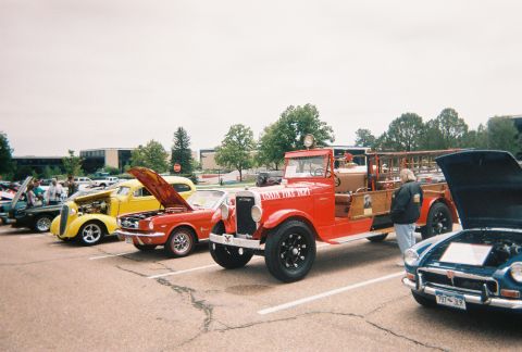 1972 Ford Ranchero - A red fire truck is parked at an outdoor car show next to other vehicles.