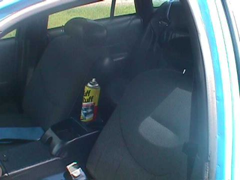1994 Ford Crown Victoria - The interior of a car shows the back seats and a can of cleaning spray on the center console.