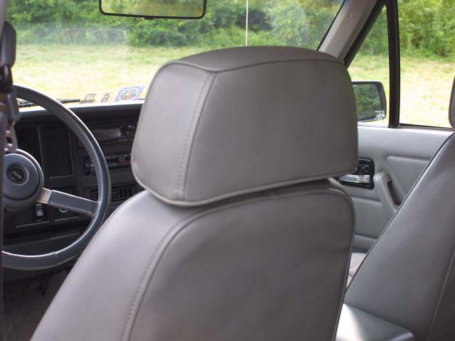 Gray interior of a vehicle showing headrest, seat, steering wheel and dashboard