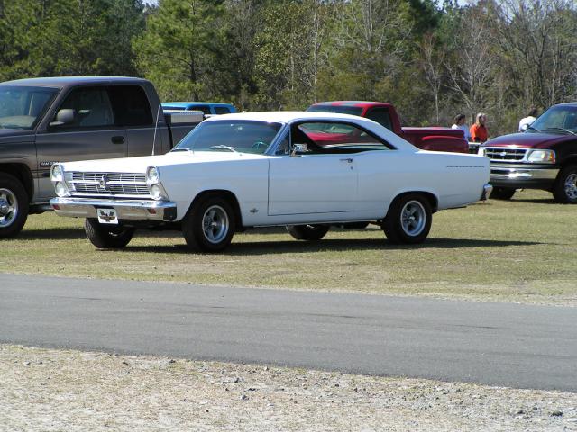 White 1966 Ford Fairlane parked on grass next to a dark pickup truck