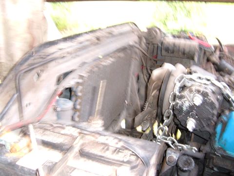 1978 Ford Bronco - The engine bay is cluttered with hoses, wires, and a large chain wrapped around a part of the engine.