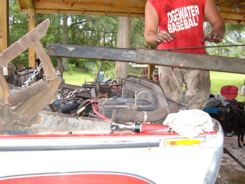 1978 Ford Bronco - A person works on the engine bay of a red and white vehicle, with tools laid out on the fender.