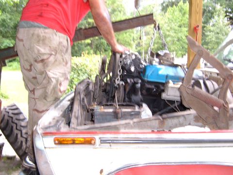 1978 Ford Bronco - Engine hoist lowering a motor into a vehicle's engine bay.