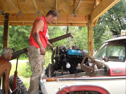 1978 Ford Bronco - An engine is being lifted out of a Ford Bronco SUV under a wooden structure.