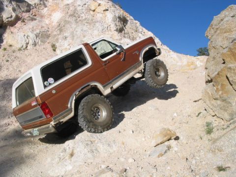 1981 Ford Bronco - This SUV navigates a challenging off-road trail under a clear blue sky.