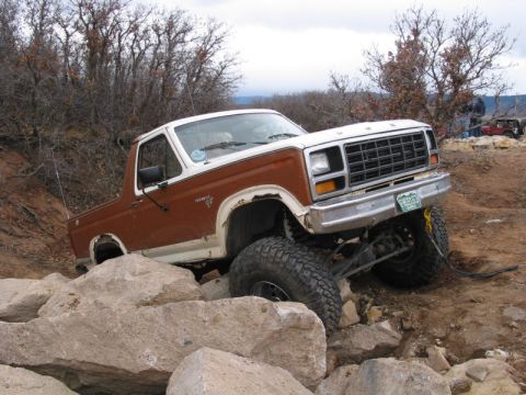 1981 Ford Bronco - This lifted Ford Bronco navigates a challenging rocky terrain, with another vehicle in the distance.
