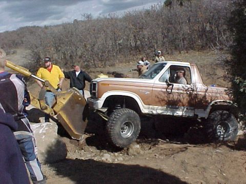 1981 Ford Bronco - A modified Ford Bronco navigates rough terrain with assistance from a backhoe.