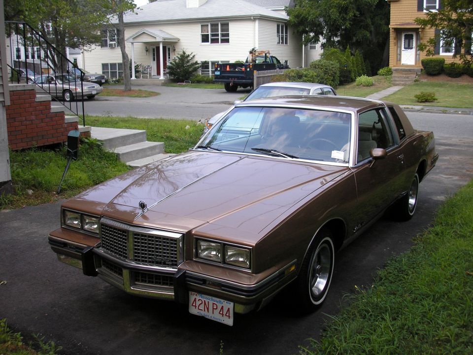 Brown Pontiac Grand Prix coupe with tan roof and Massachusetts plate 42N P44 in a driveway
