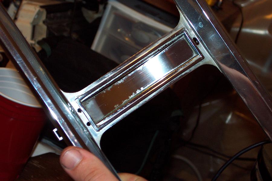Chrome trim piece with a rectangular inset, showing wear and scratches