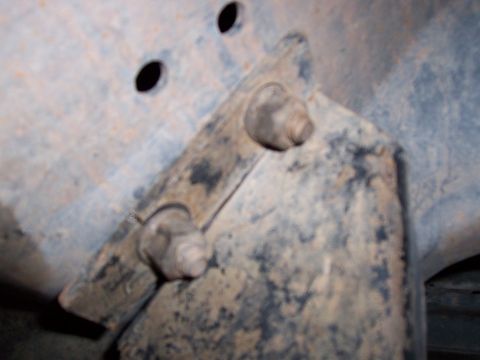 1991 Ford Bronco - Close-up of a dirty, corroded metal bracket and bolts, likely from a vehicle's chassis.