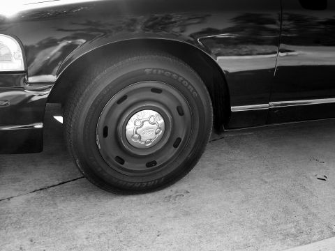 2003 Ford Crown Victoria - Front wheel and fender detail of a 2003 Ford Crown Victoria, showing the Firestone tire and Ford hubcap.
