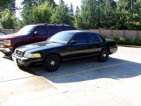 2003 Ford Crown Victoria - A black 2003 Ford Crown Victoria sedan is parked next to a maroon SUV.