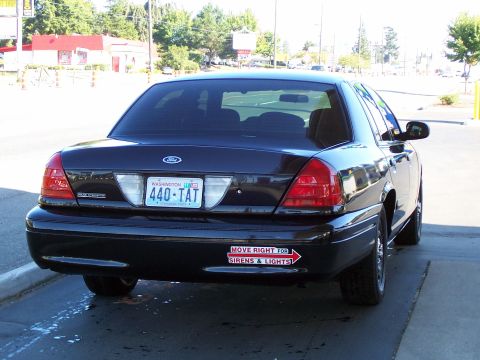 2003 Ford Crown Victoria - Rear view of a black 2003 Ford Crown Victoria, showing its license plate and a safety sticker.