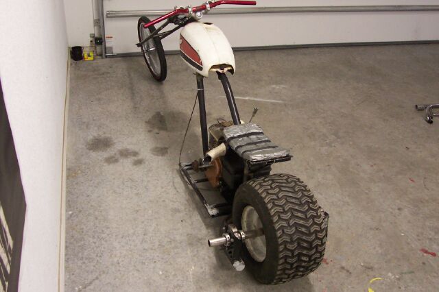 Custom motorized scooter with a white and red gas tank, a large rear tire, and a metal frame