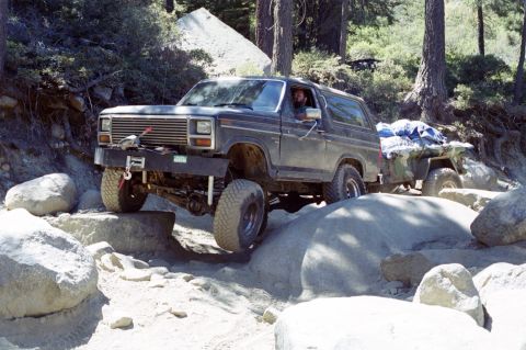 1967 Ford Bronco - Ford Bronco off-roading on a rocky trail, towing a trailer.