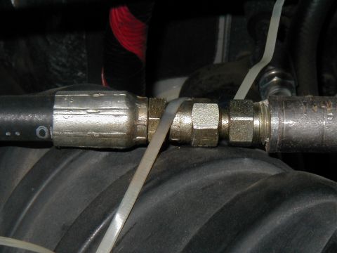 2002 Ford Excursion - A close-up view of a hydraulic hose assembly, showing the metal fittings and a securing zip tie.