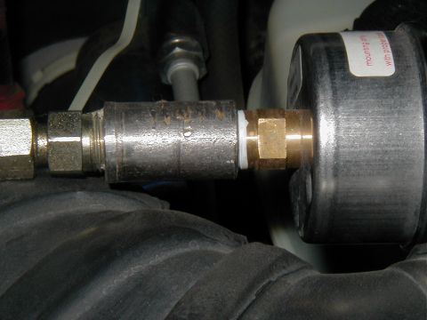 2002 Ford Excursion - A close-up view of automotive plumbing connected to a gauge, with visible text on a sticker.