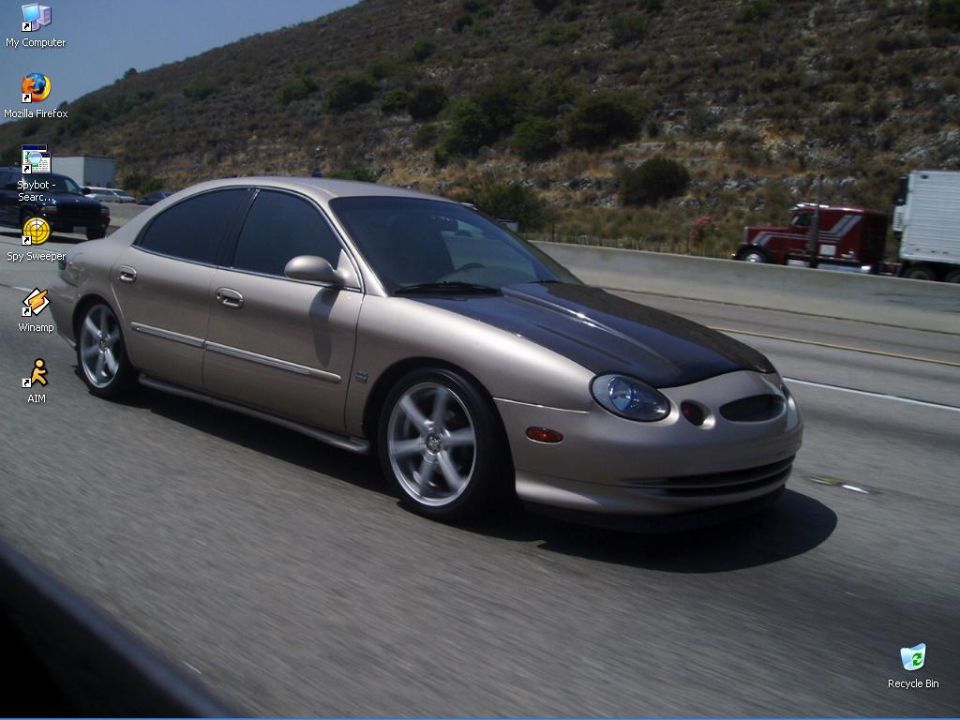 Tan sedan with a black hood driving on the highway