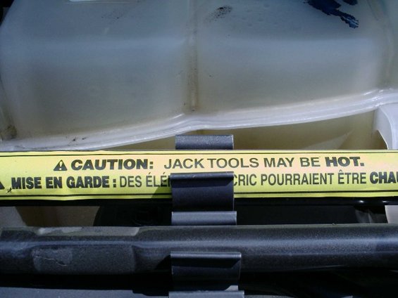 Bilingual caution decal reading JACK TOOLS MAY BE HOT near a translucent reservoir