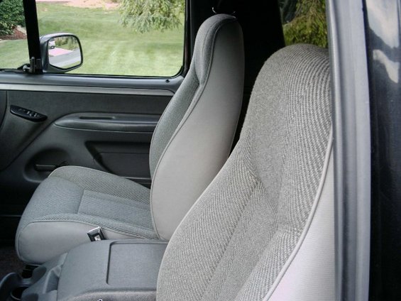 Gray cloth bucket seat interior with door panel and window view of grass