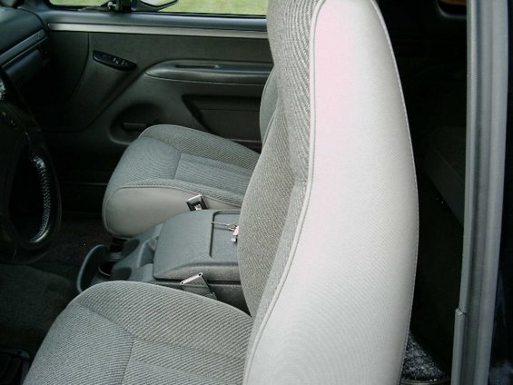 Gray cloth bucket seats slid forward in a truck cab, viewed through the passenger door