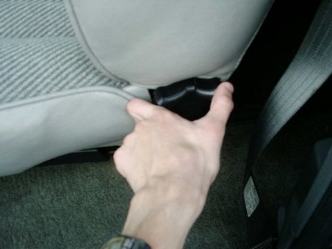 1992 Ford Bronco - A hand operates the seat adjustment lever inside a vehicle.