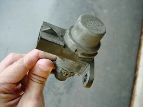 1992 Ford Bronco - A Ford engine sensor part is held in a hand against a blurred background.