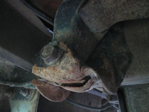 1992 Ford Bronco - Close-up view of a severely corroded and damaged vehicle suspension component.