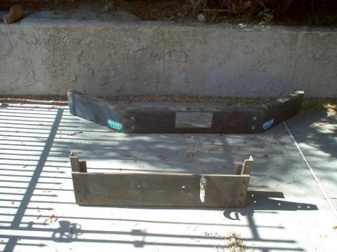 1988 Ford Bronco - A fabricated steel front winch bumper for a truck or SUV sits on a concrete pad in front of a stucco retaining wall, with a separate winch…