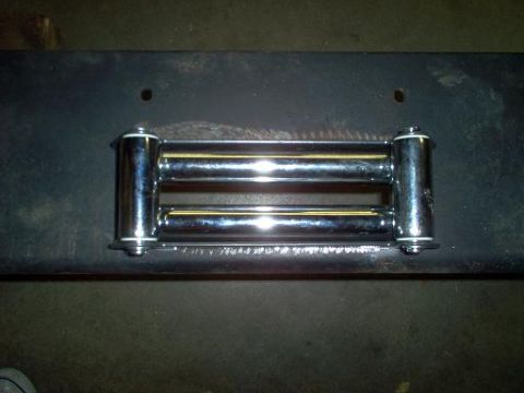 1988 Ford Bronco - Close-up of a chrome winch fairlead with rollers, mounted on a dark metal surface.