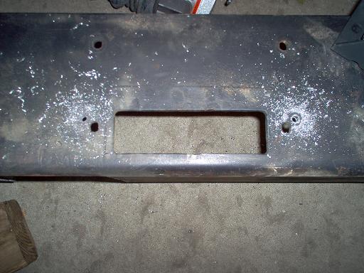 Bare steel bumper on garage floor with rectangular winch opening cut in center