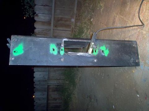 1988 Ford Bronco - A metal bumper part, marked with green spray paint, lies on the ground.