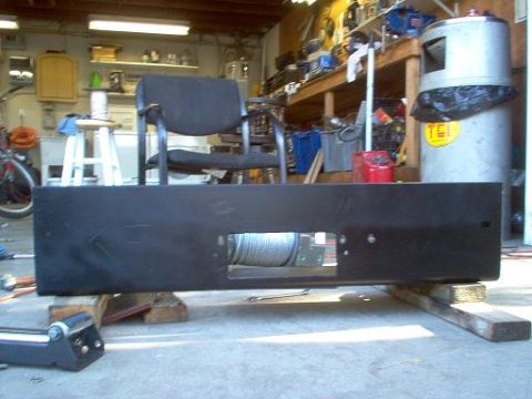 1988 Ford Bronco - A black winch and bumper assembly is shown resting on wooden blocks in a garage setting.